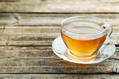 Aromatic black tea in glass cup on wooden table, closeup. Space for text