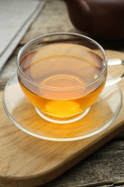 Aromatic black tea in glass cup on wooden table, closeup