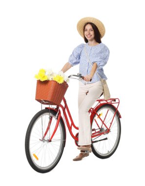 Beyaz arka planda çiçek sepeti olan şapkalı ve bisikletli gülümseyen kadın.