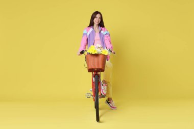 Gülümseyen kadın ve bisiklet Çiçek sepeti ile sarımsı yeşil arka planda