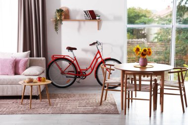 Odasında sandalye, kanepe ve bisiklet olan ahşap yemek masası.