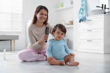 Anne banyoda bebeğinin saçını tarıyor.