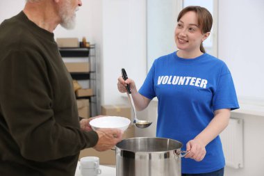 Yaşlılar için insani yardım. Gönüllü içeride kıdemli bir adama yemek veriyor.