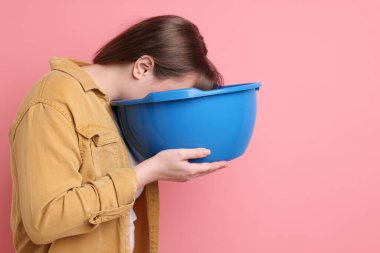 Pembe arka planda mide bulantısı çeken bir kadın. Metin için boşluk