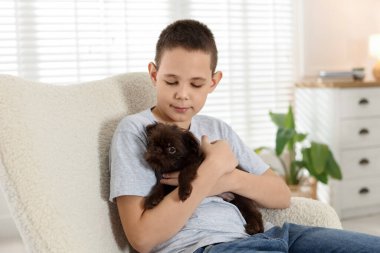 Evdeki koltukta şirin bir Griffon köpeği olan çocuk. Evcil hayvan