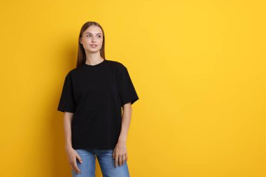 Sarı arka planda şık siyah tişört giyen bir kadın. Tasarım için model