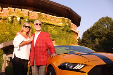 Modern Cabriolet yakınlarında güneş gözlüklü şık bir çift, düşük açılı.