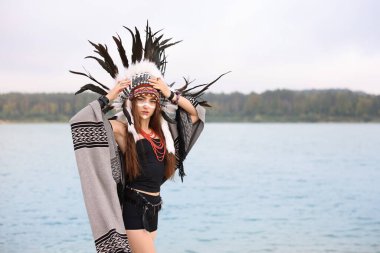 Kızılderili başlıklı güzel bir şaman kadın portresi. Yüzü boyalı ve nehir kenarında mücevherleri var. Metin için boşluk