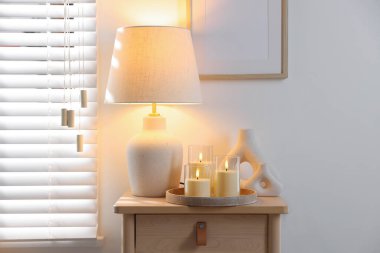 Decorative LED candles, vases and lamp on wooden table indoors