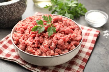 Maydanozlu çiğ et ve gri masada baharatlar, yakın plan.