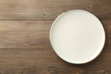 Clean ceramic plate on wooden table, top view. Space for text