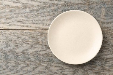 Clean ceramic plate on wooden table, top view. Space for text
