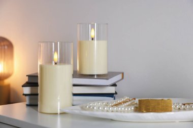 Dekoratif LED mumlar, kitaplar ve mücevherler beyaz masa içinde, yakın plan.