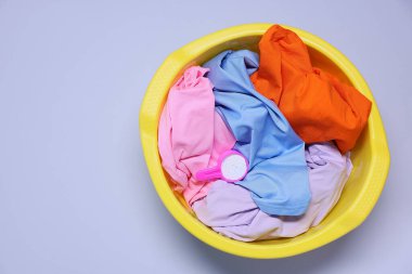 Plastik leğen ve açık mor arka planda çamaşır deterjanı, üst manzara. Metin için boşluk