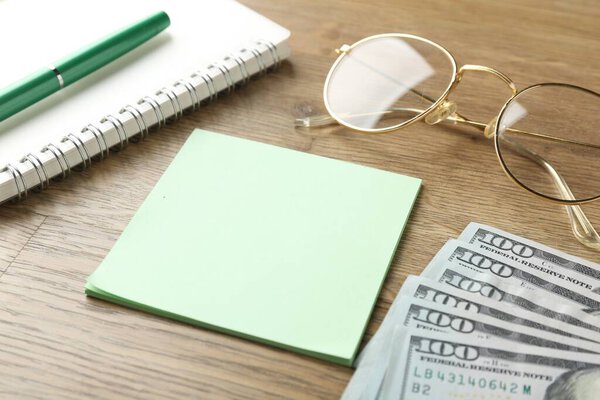Алименты. Липкие банкноты, деньги, блокнот, ручка и очки на деревянном столе, крупный план