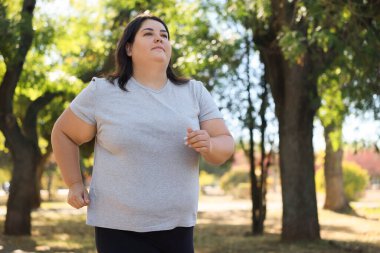 Kilolu bir kadın dışarıda koşuyor, düşük açılı. Metin için boşluk