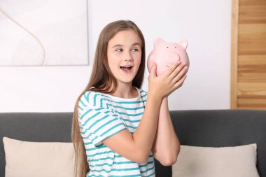 Cep harçlığı. Evdeki kanepede kumbaralı kız.