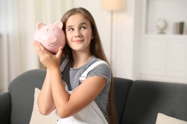 Cep harçlığı. Evdeki kanepede kumbaralı kız.