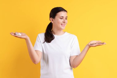 Turuncu arka planda gözlük ve kontak lens arasında seçim yapan genç bir kadın.