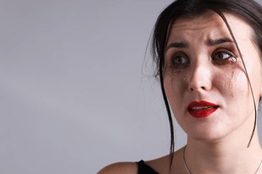 Gri arka planda ağlayan, maskara bulaşmış bir kadın, yakın plan. Metin için boşluk