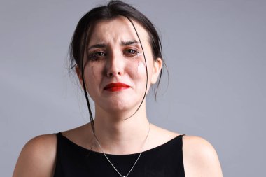 Gri arka planda ağlayan lekeli rimeli olan kadın.