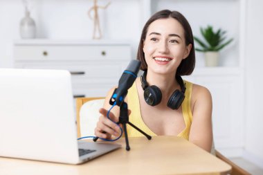 Kapalı mekanda mikrofon ve dizüstü bilgisayarlı Podcast sunucu kayıt bölümü