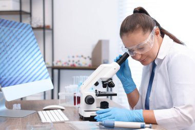 Genetik araştırması. Laboratuardaki masada mikroskopla çalışan bilim adamı.