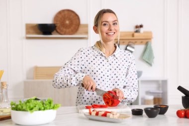 Yemek pişirme süreci. Mutfakta masada biber kesen gülümseyen kadın.