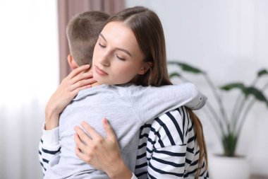 Anne, üzgün oğlunu evde destekleyip kucaklıyor.