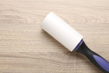 Sticky lint roller on wooden table, top view. Space for text
