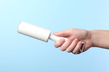 Açık mavi arka planda pamuklu silindirli kadın, yakın plan.