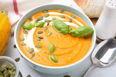 Beyaz masada servis edilen lezzetli balkabağı çorbası, yakından.