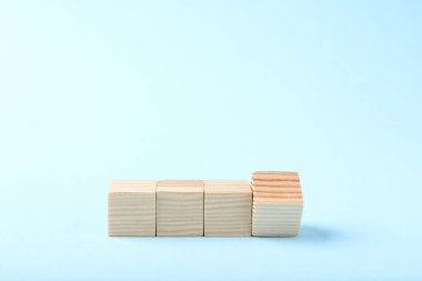 Blank wooden cubes on light blue background, space for text