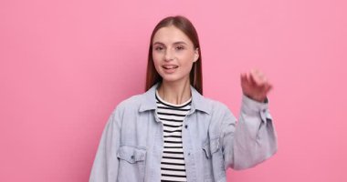 Pembe arka planda el ele hareketler gösteren bir kadın.