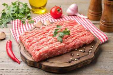 Maydanozlu çiğ et ve ahşap masada baharatlar, yakın plan.