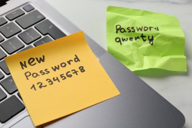 Şifre değiştiriliyor. Yeni ve eski şifreli kâğıt notlar ve beyaz masada dizüstü bilgisayar