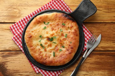 Delicious Megrelian khachapuri with parsley served on wooden table, top view