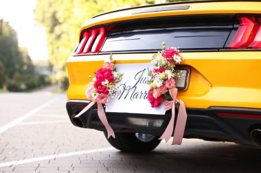 Düğün arabası. Cabriolet dekore edilmiş. Sadece evlilik kartı ve açık havada güzel çiçekler, yakın plan.