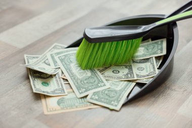 Dollar banknotes, dustpan and broom on floor, closeup