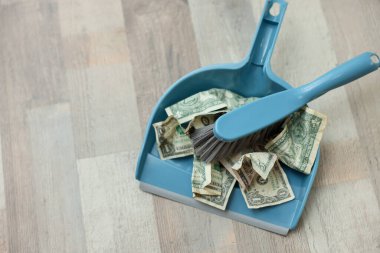 Bir dolarlık banknotlar, yerdeki faraş ve süpürge, yakın plan. Metin için boşluk