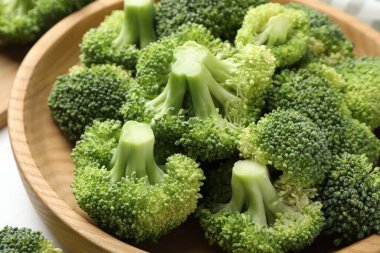 Fresh green broccoli in bowl on white table, closeup