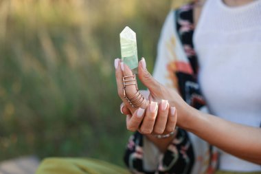 Kadın dışarıda atmosferini iyileştirmek ya da iyileştirmek için kristalle meditasyon yapıyor. Metin için boşluk