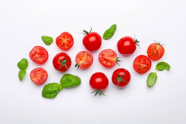 Beyaz arka planda taze kırmızı domates ve fesleğen yaprakları.