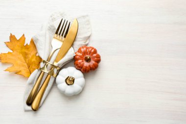 Beautiful table setting. Cutlery with napkin and autumn decor on white wooden background, top view. Space for text