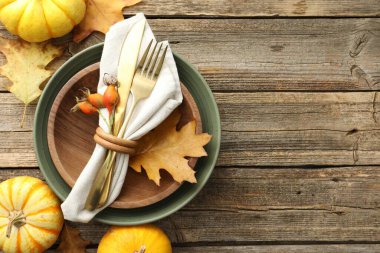 Beautiful table setting with autumn decor on wooden background, flat lay. Space for text