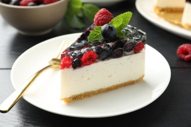 Lezzetli peynirli kek, böğürtlenli ve nane şekerli, siyah ahşap masa, yakın plan.