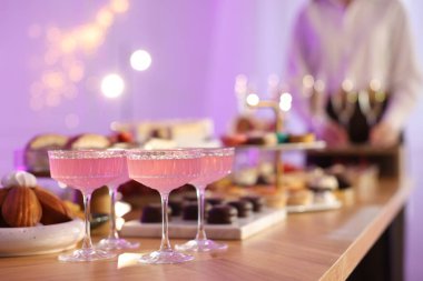 Different delicious desserts, drinks on buffet table and waiter, selective focus