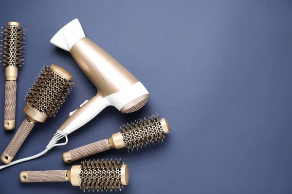 Koyu mavi arka planda farklı saç şekillendirme araçları, düz yatış. Metin için boşluk