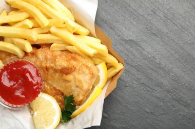 Soslu, limonlu ve maydanozlu İngiliz Geleneksel Balık ve patates kızartması. Koyu dokulu masa, üst manzara. Metin için boşluk