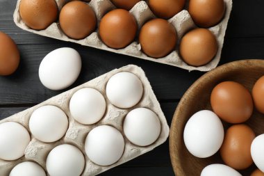 Pek çok çiğ tavuk yumurtası siyah ahşap masanın üzerinde, düz yatıyordu.